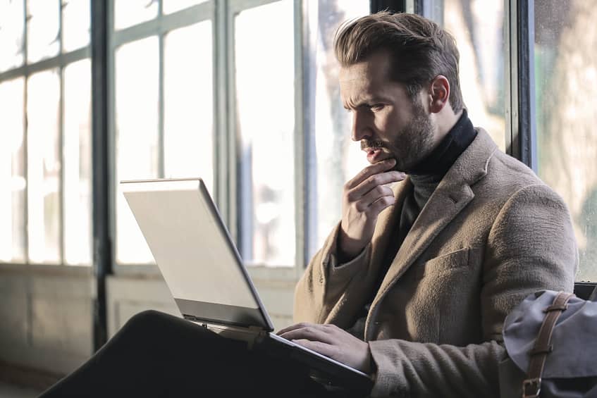 A man in front of a laptop thinking